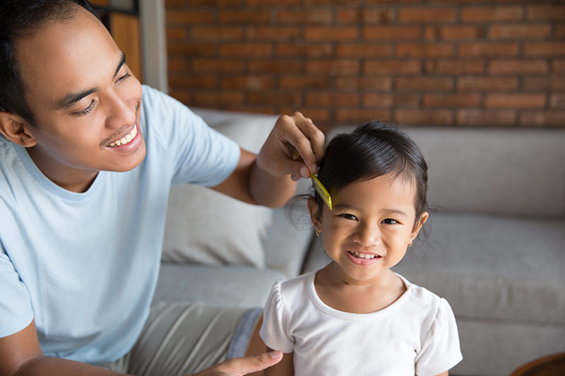Indonesian dad combing daughter's hair